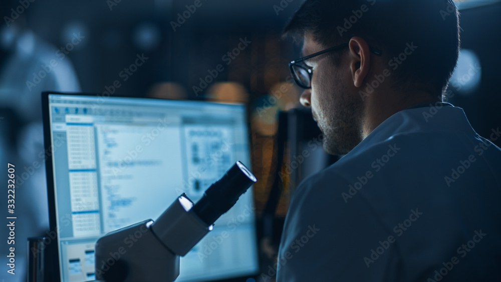 Shot of a Male IT Scientist Uses Computer Showing System Monitoring and Controlling Program. In the 