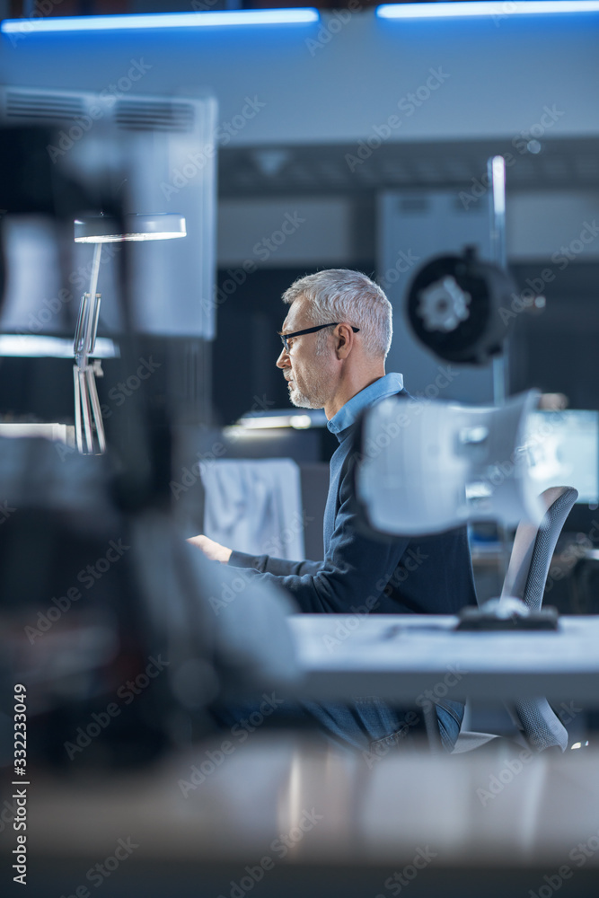 Shot of Industrial Engineer Working in Research Laboratory / Development Center, Using Computer. He 