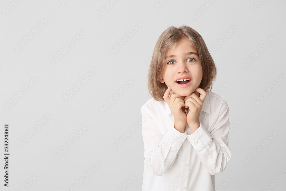 Happy little girl with healthy teeth on light background