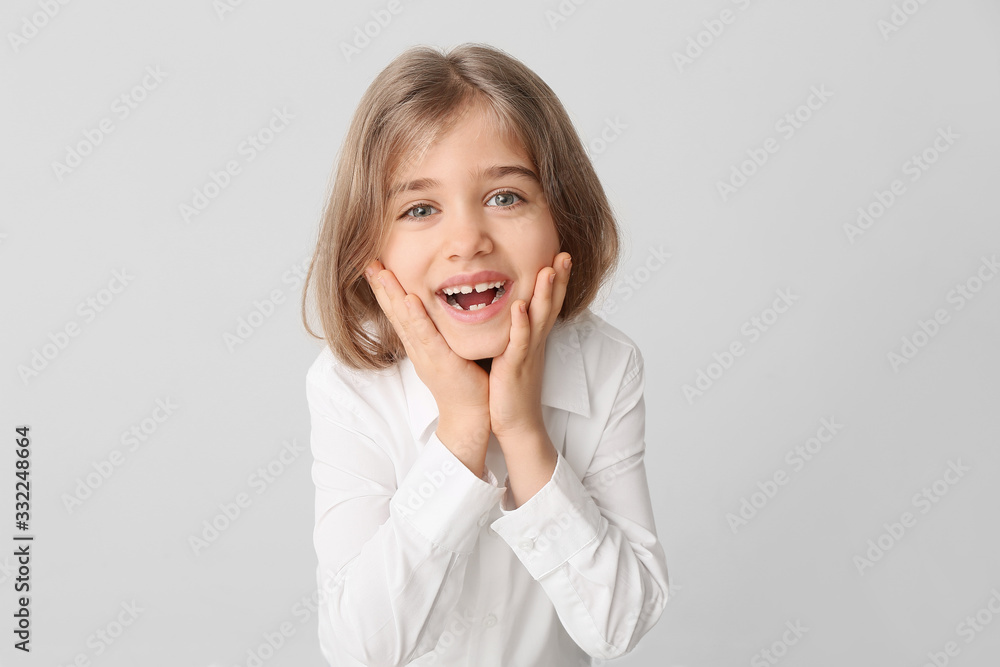 Happy little girl with healthy teeth on light background