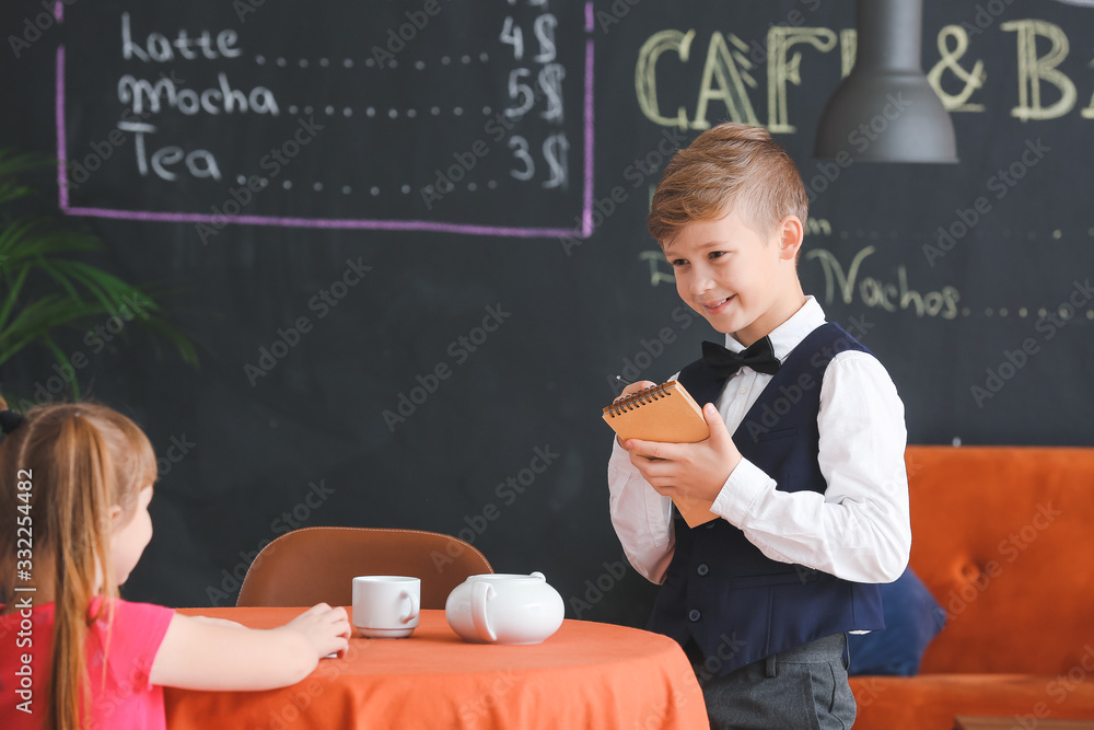 Cute little waiter serving client in restaurant