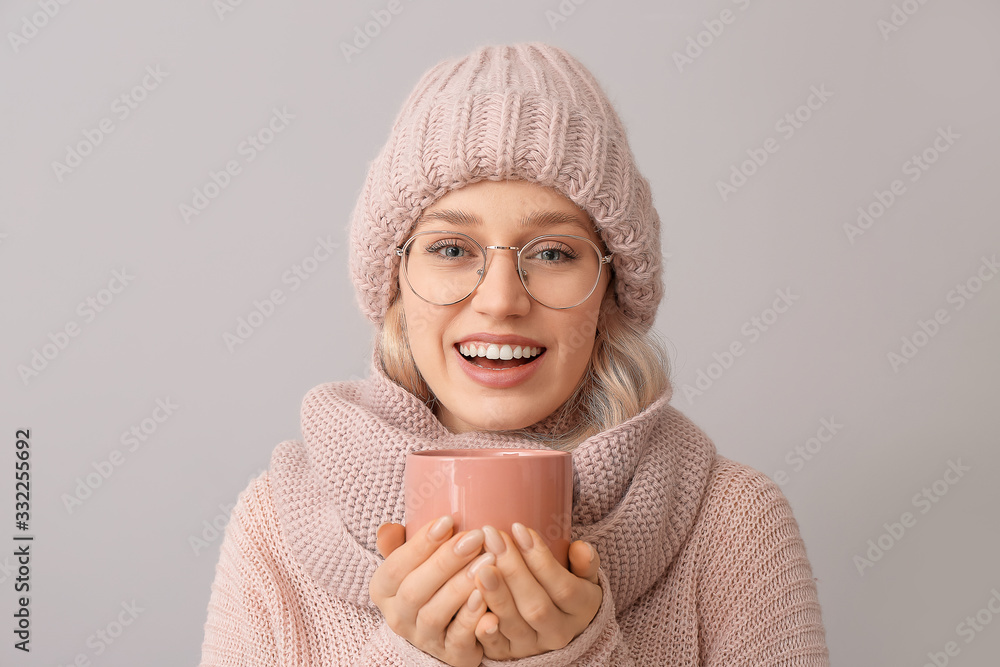 Beautiful young woman with cup of tea on grey background