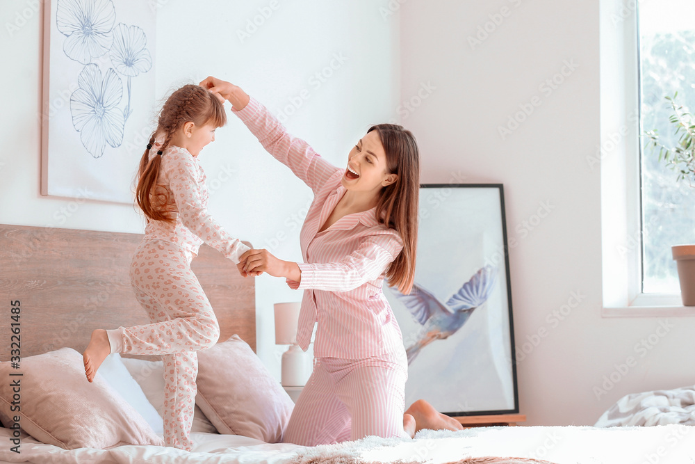 Morning of happy mother and her little daughter dancing in bedroom