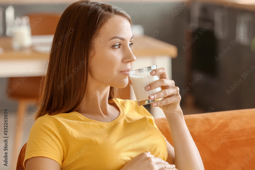 Beautiful pregnant woman drinking milk at home