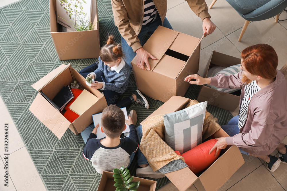 Family unpacking moving boxes in their new house, top view