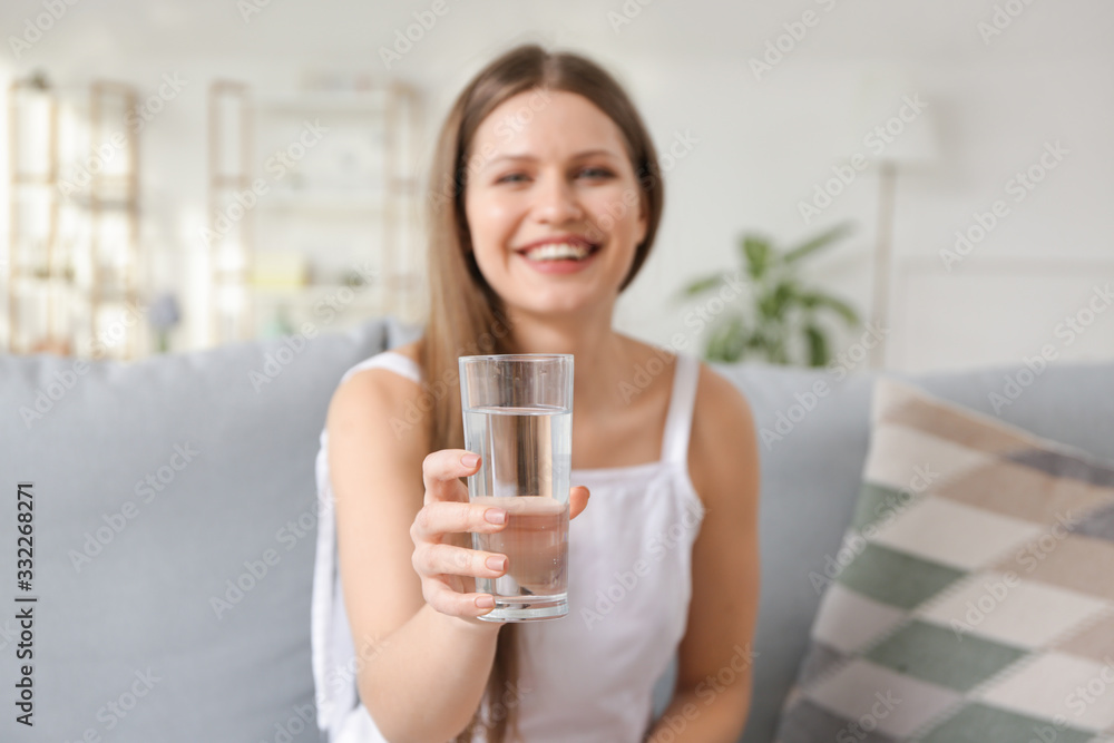 Beautiful young woman drinking water at home