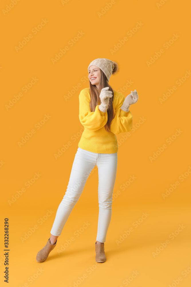 Beautiful young woman in warm sweater on color background