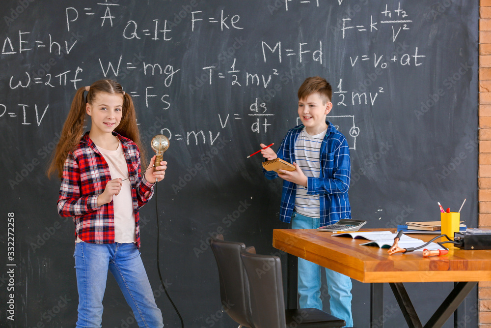 Cute little children near blackboard at physics lesson in classroom