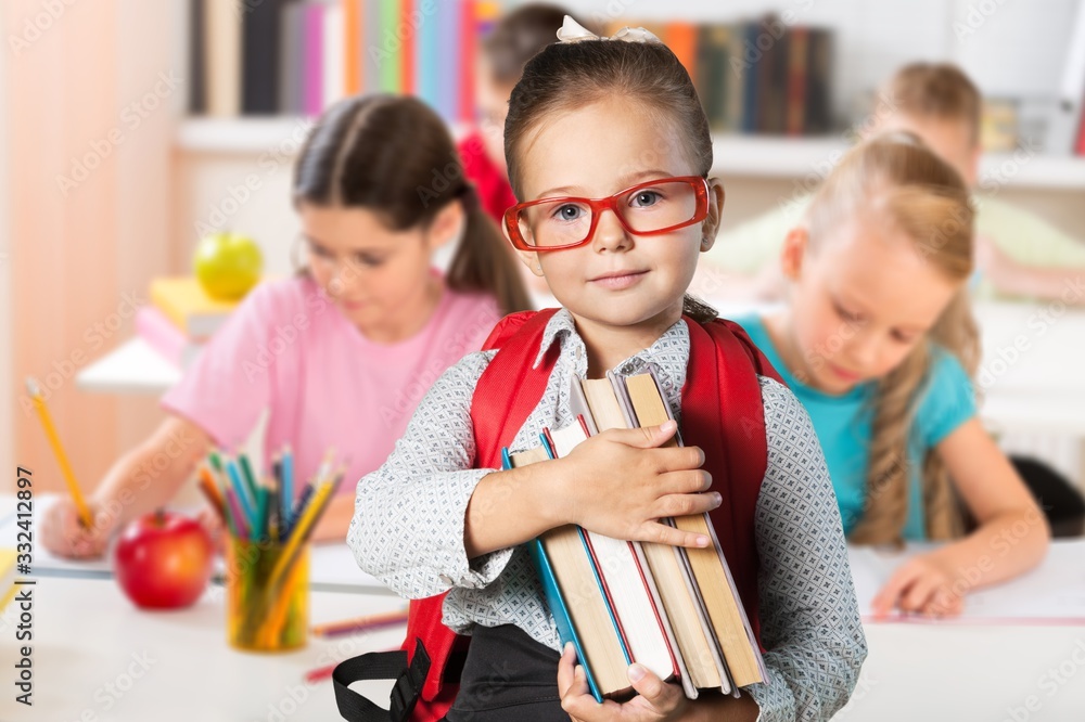 Cute little schoolgirl in glasses holding books