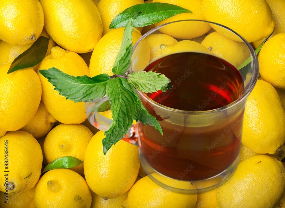 Set of fresh yellow lemons on desk and tea in the glass