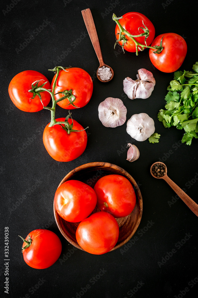 Tomatoes harvest. Vegetables near garlic, greenery and spices on black background top-down