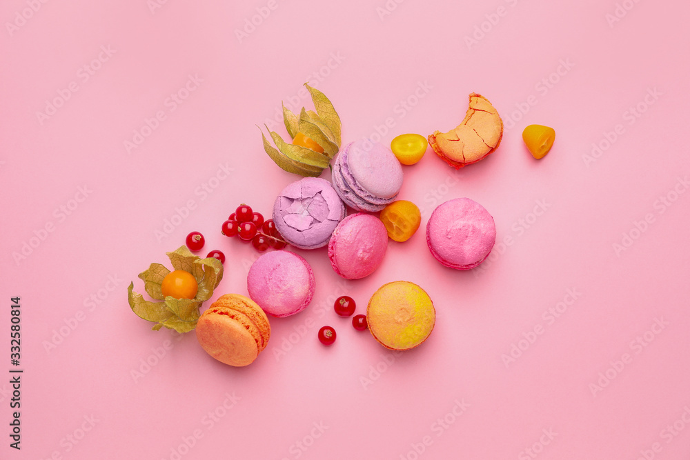 Tasty macarons with fruits on color background