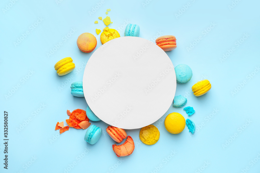 Tasty macarons with paper sheet on color background