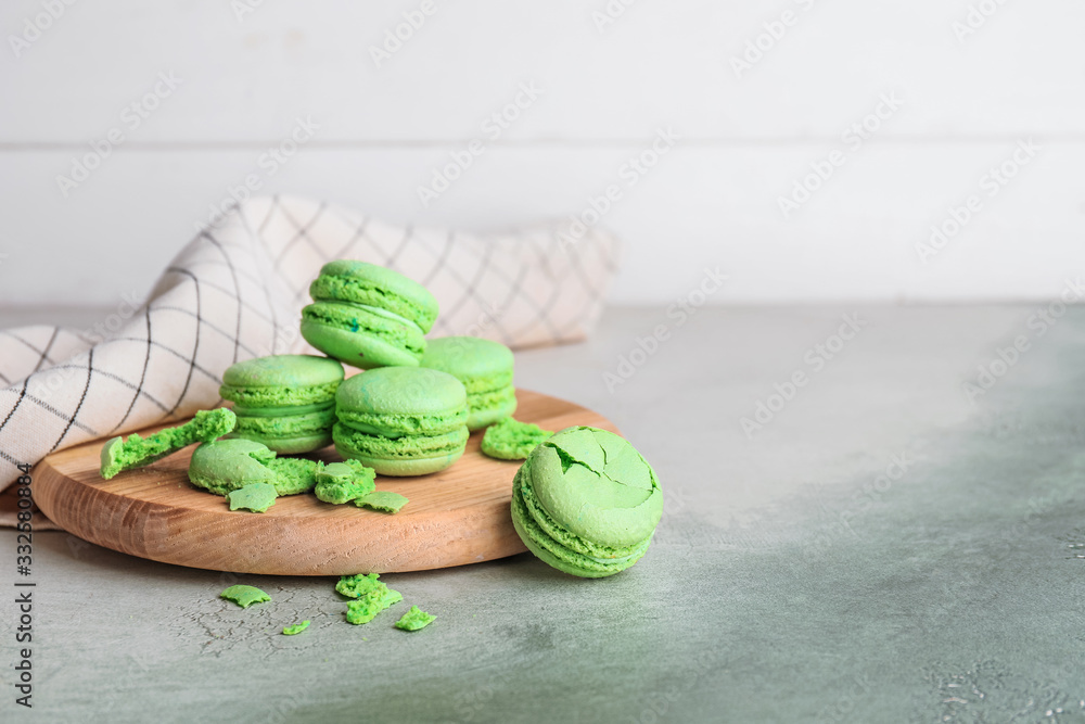 Board with tasty macarons on table