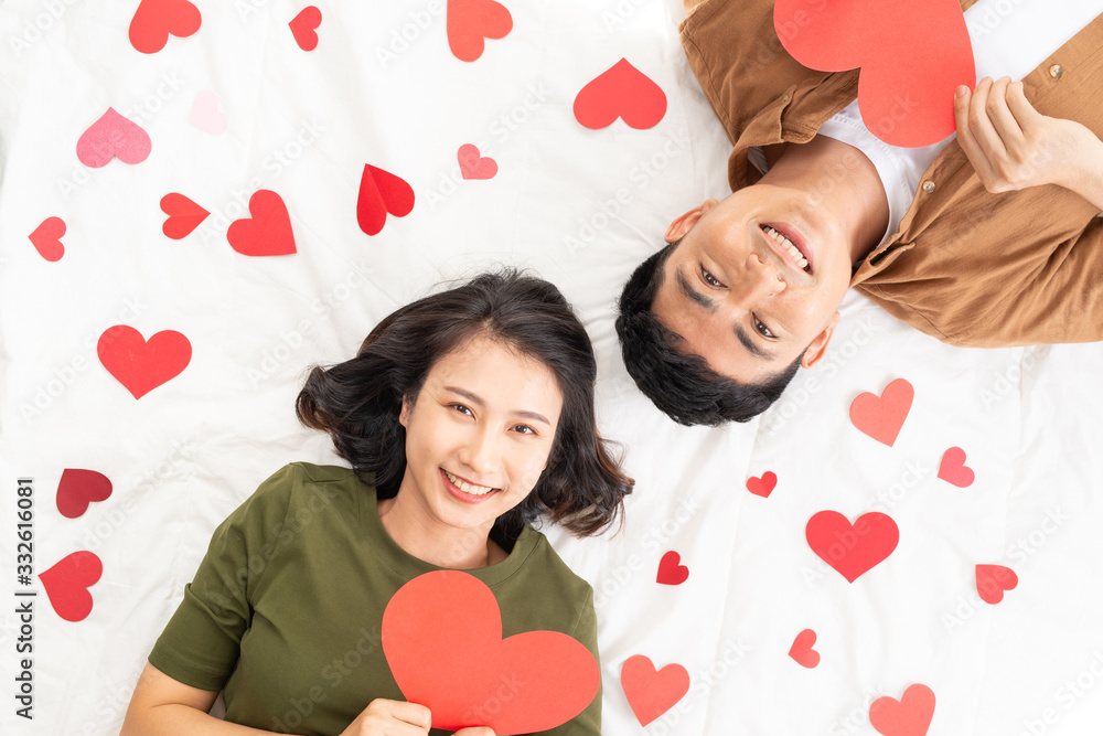 Self portrait of sweet cute couple lying head to head on the floor with small red hearts