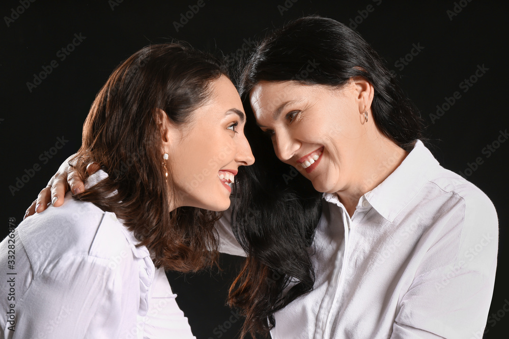 Portrait of adult daughter and her mother on dark background