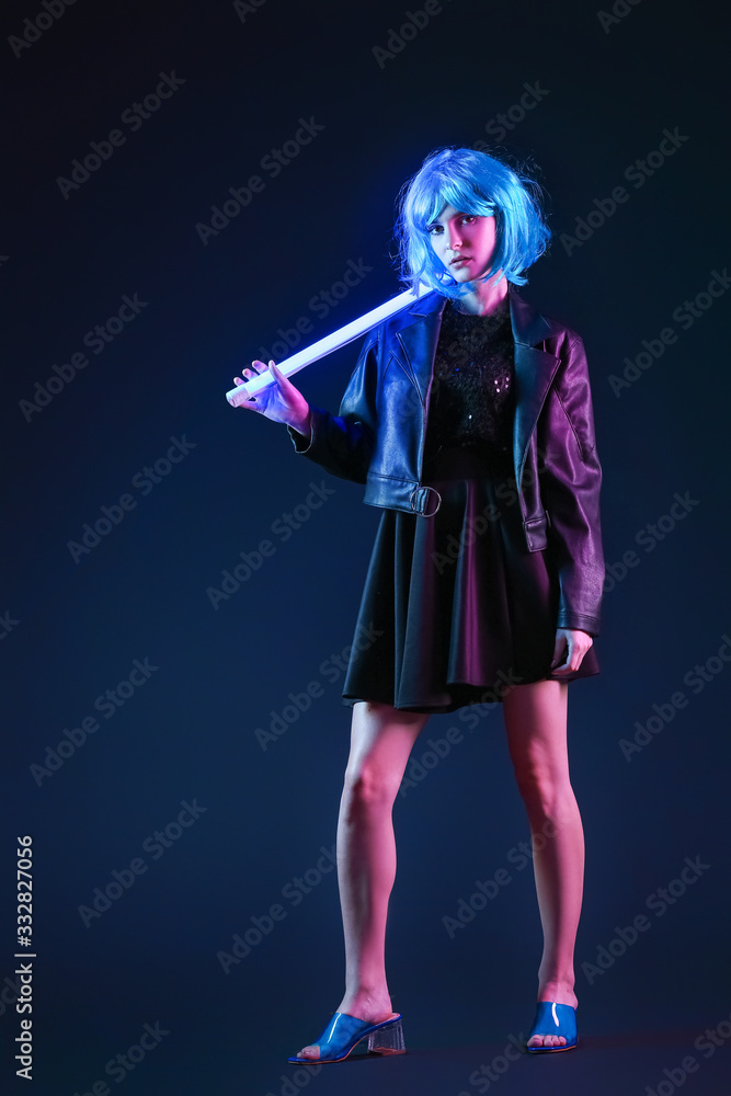 Toned portrait of beautiful woman with neon lamp on dark background