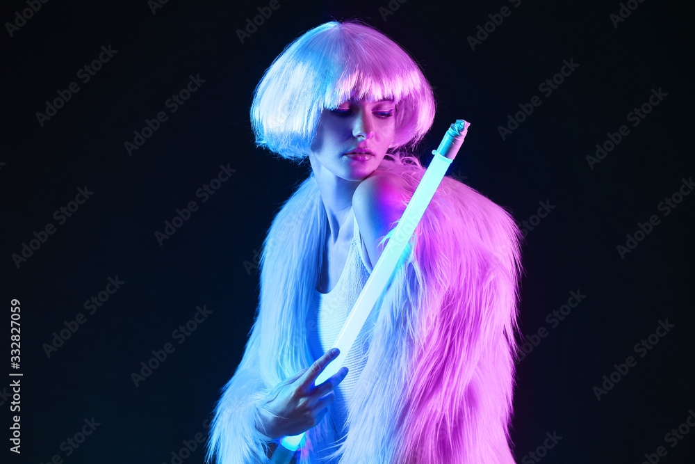 Toned portrait of beautiful woman with neon lamp on dark background