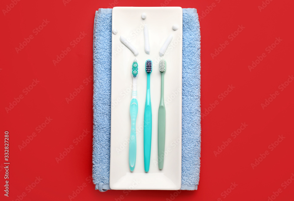 Tooth brushes with paste and towel on color background