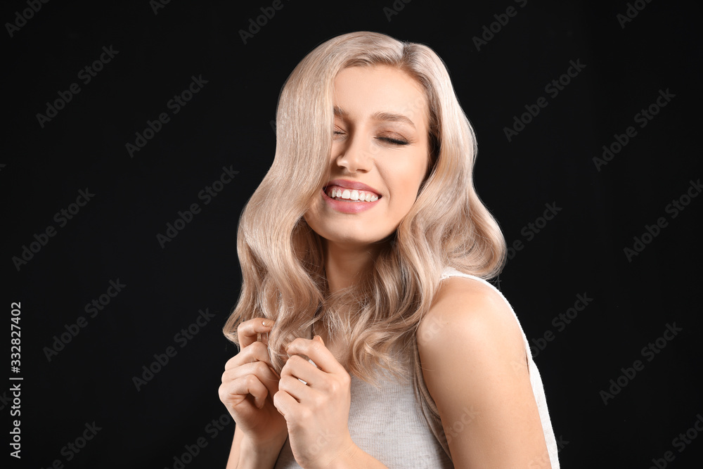 Young blonde with beautiful hair on dark background