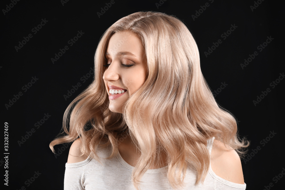 Young blonde with beautiful hair on dark background