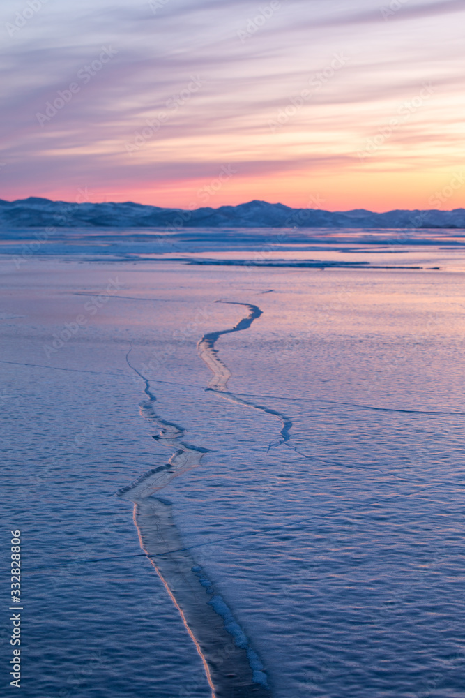 Frozen winter landscape of ice on lake Baikal during a colorful sunset. Lake Baikal, Siberia, Russia