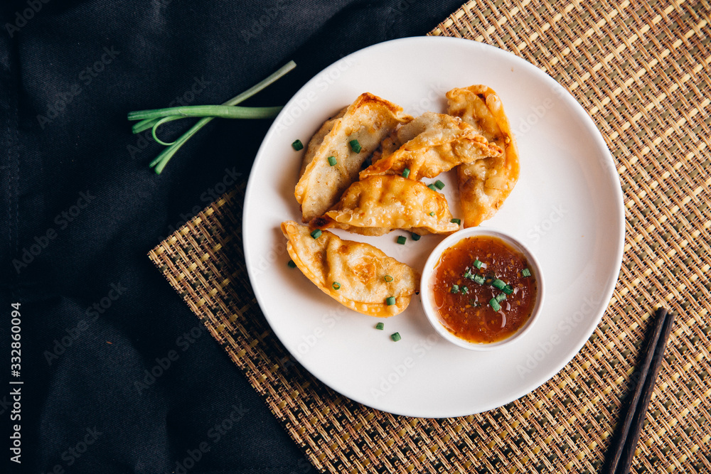 亚洲饺子Gyozas锅贴在铸铁锅上油炸，用筷子和一碗酱油食用