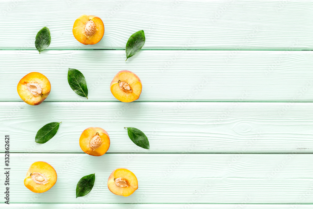 Peach slices and leaves pattern on green wooden background top-down copy space frame