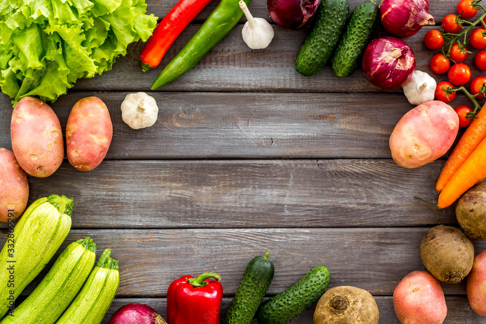 Set of autumn vegetables - potato, cucumber, carrot, greenery - on dark wooden background top-down c