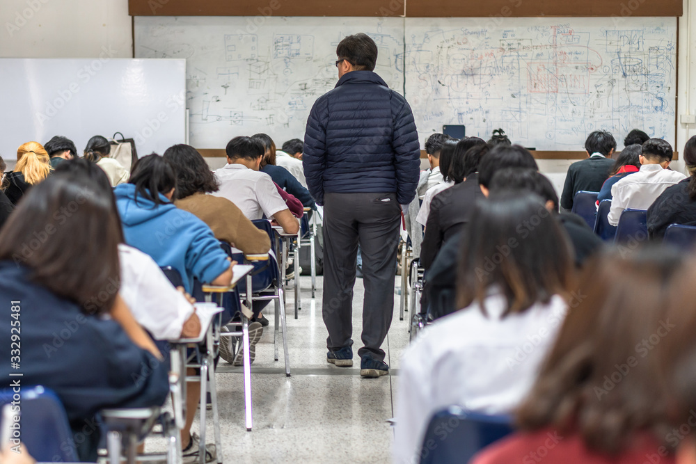 学校考场，有老师（监考老师）监督学生在课堂上参加教育考试