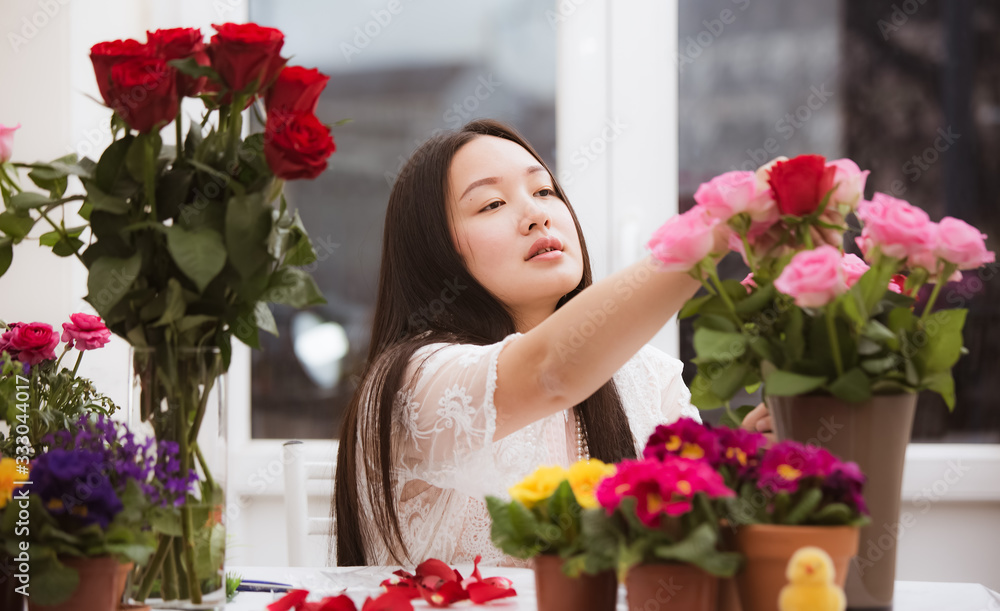 准备在家里修剪红色和粉色玫瑰以及美丽的插花的女人，花arr