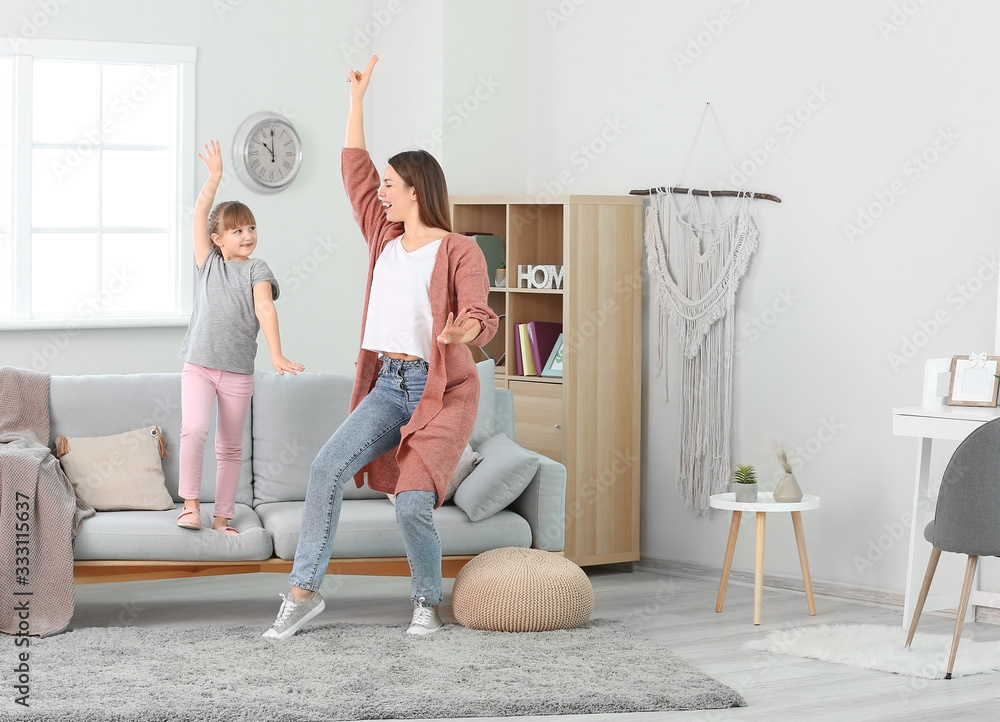 Happy mother and her little daughter dancing at home