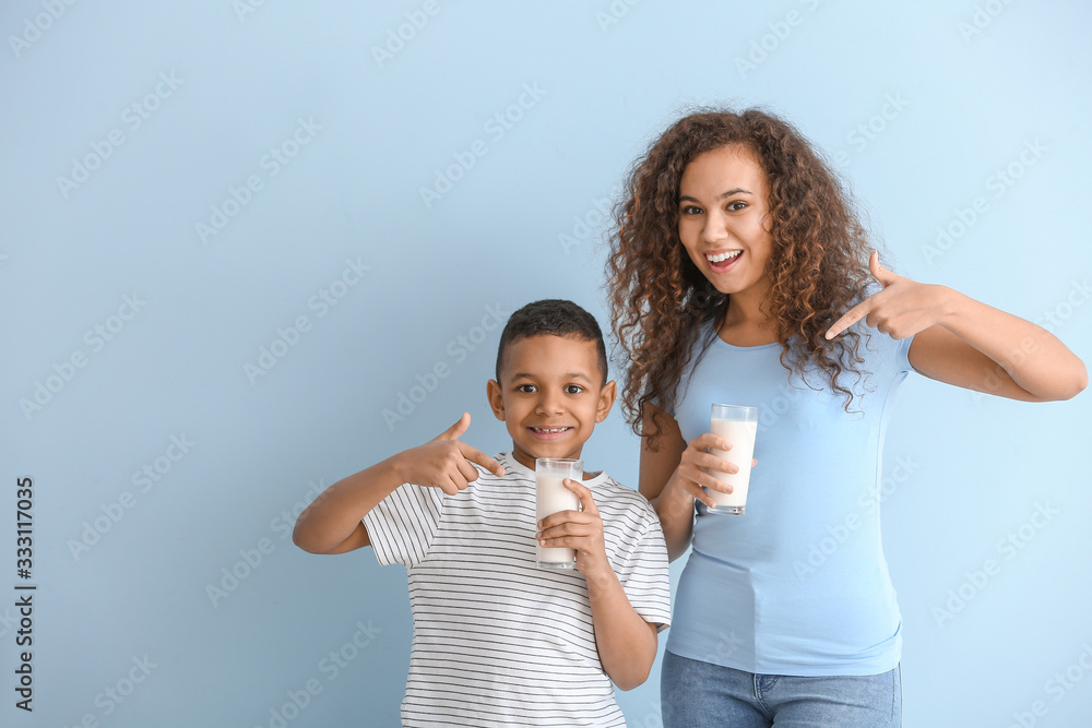 African-American woman and her son with milk on color background