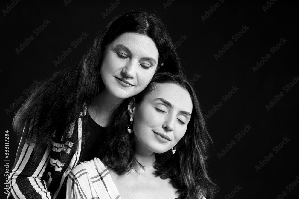 Black and white portrait of adult daughter and her mother on white background