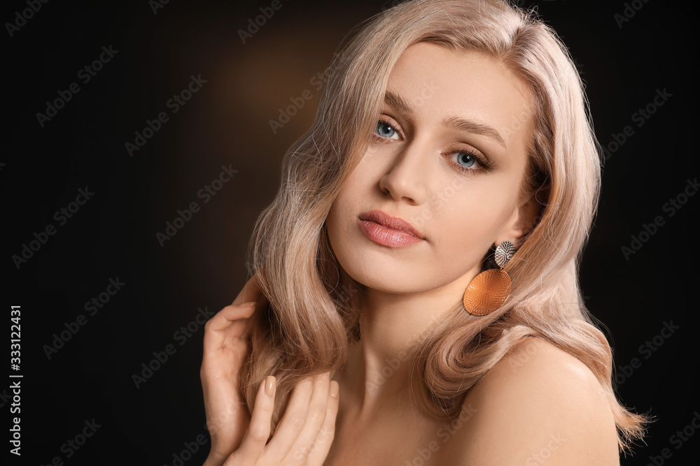 Young blonde with beautiful hair on dark background