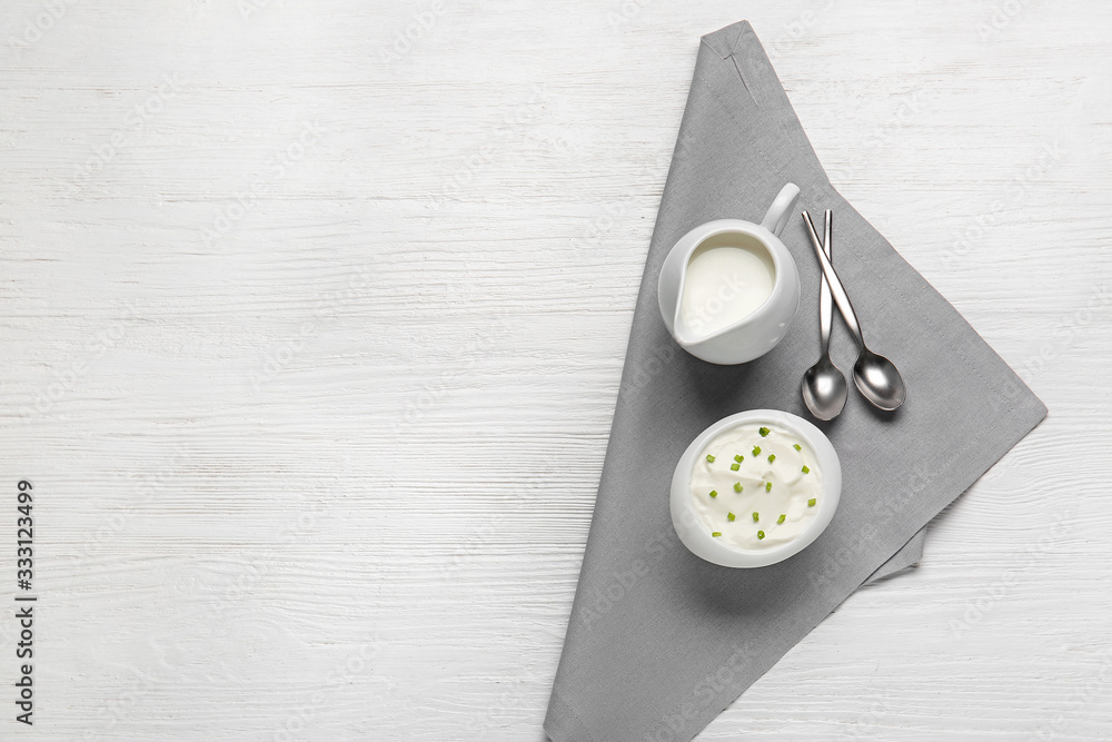 Bowl of tasty sour cream and milk on table