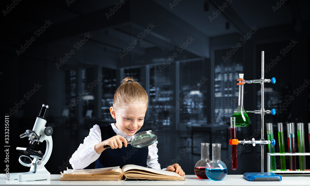 Little girl sitting at desk with magnifier