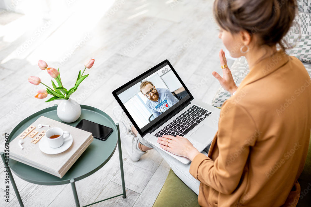 Business woman having a video call with coworker, working online from home at cozy atmosphere