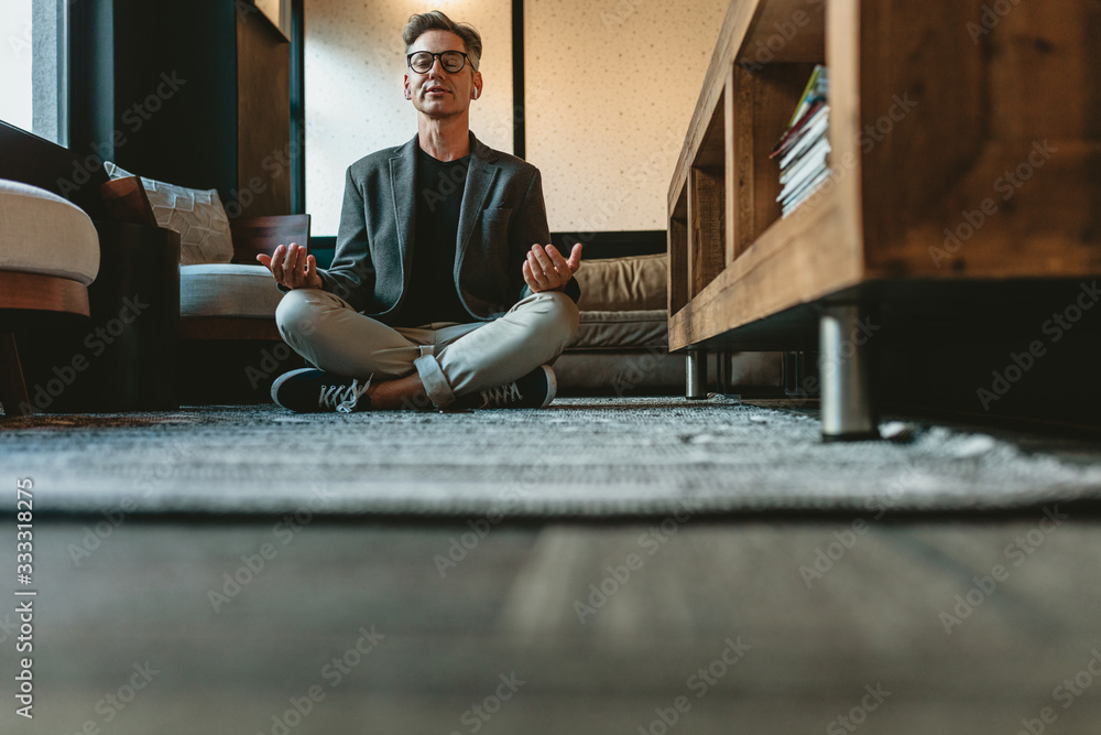 Mid adult businessman doing yoga meditation in office