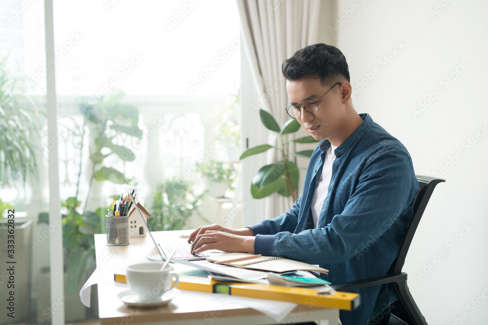 Portrait of a smiling young businessman working on blueprints at the office