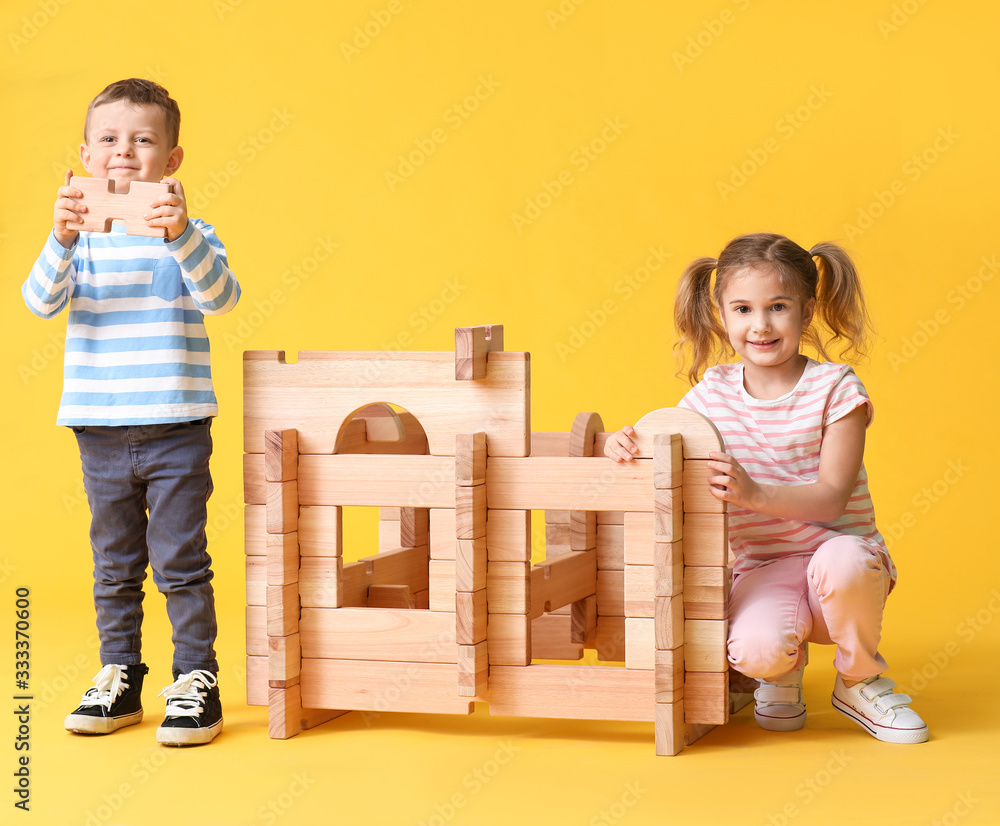 Little children playing with take-apart house on color background