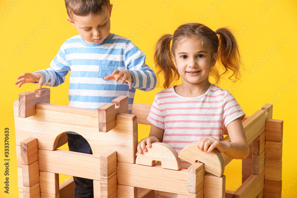 Little children playing with take-apart house on color background