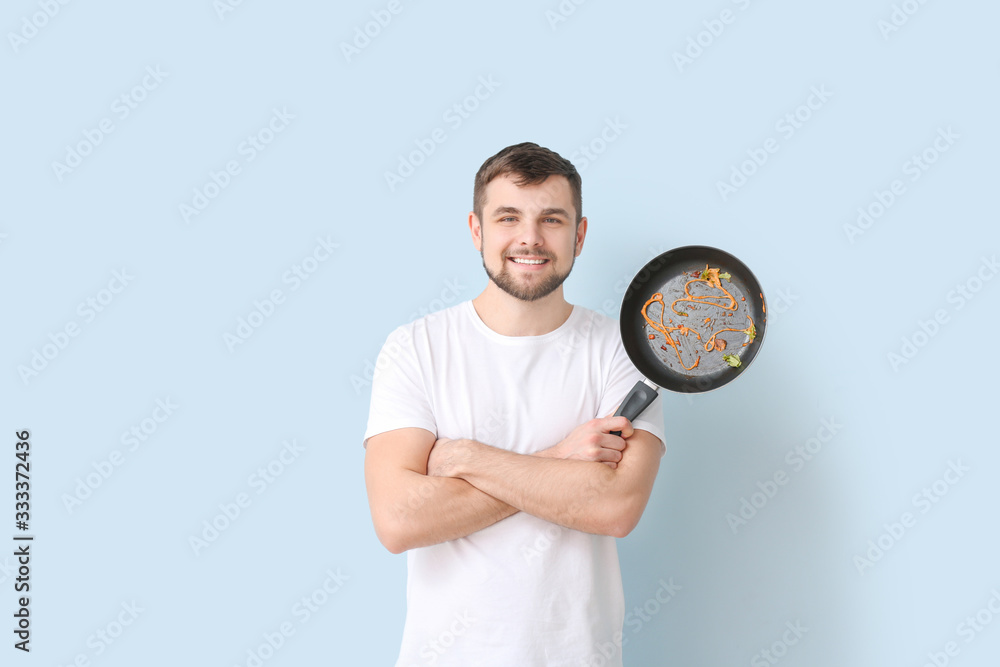 Man with dirty frying pan on color background