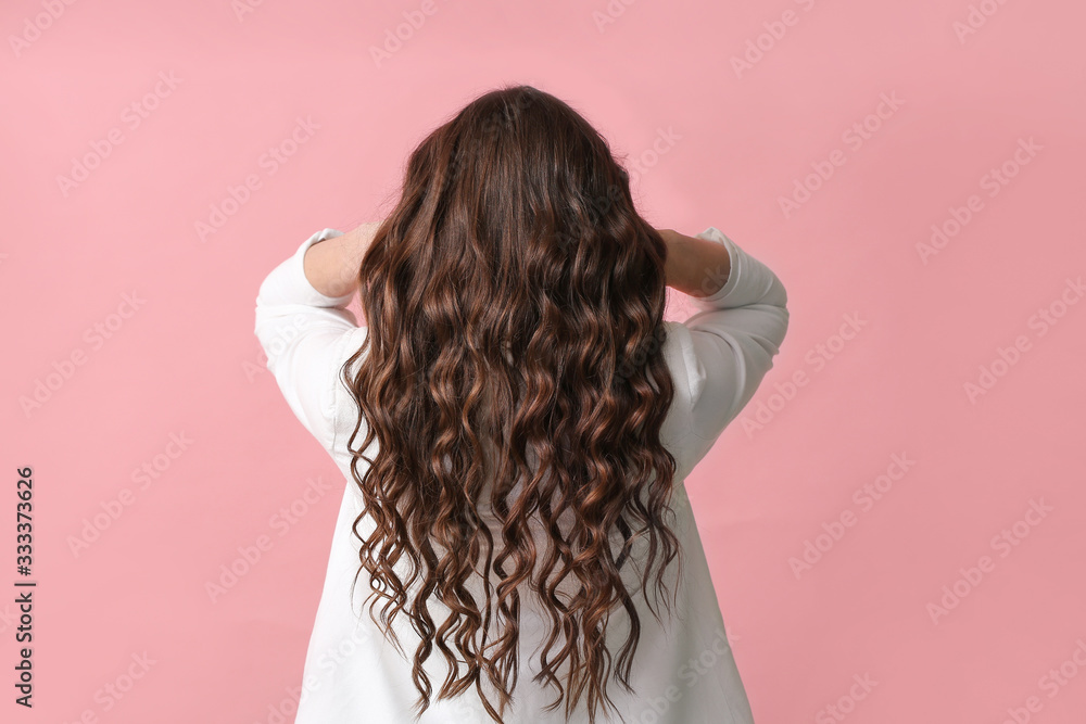 Young woman with beautiful wavy hair on color background