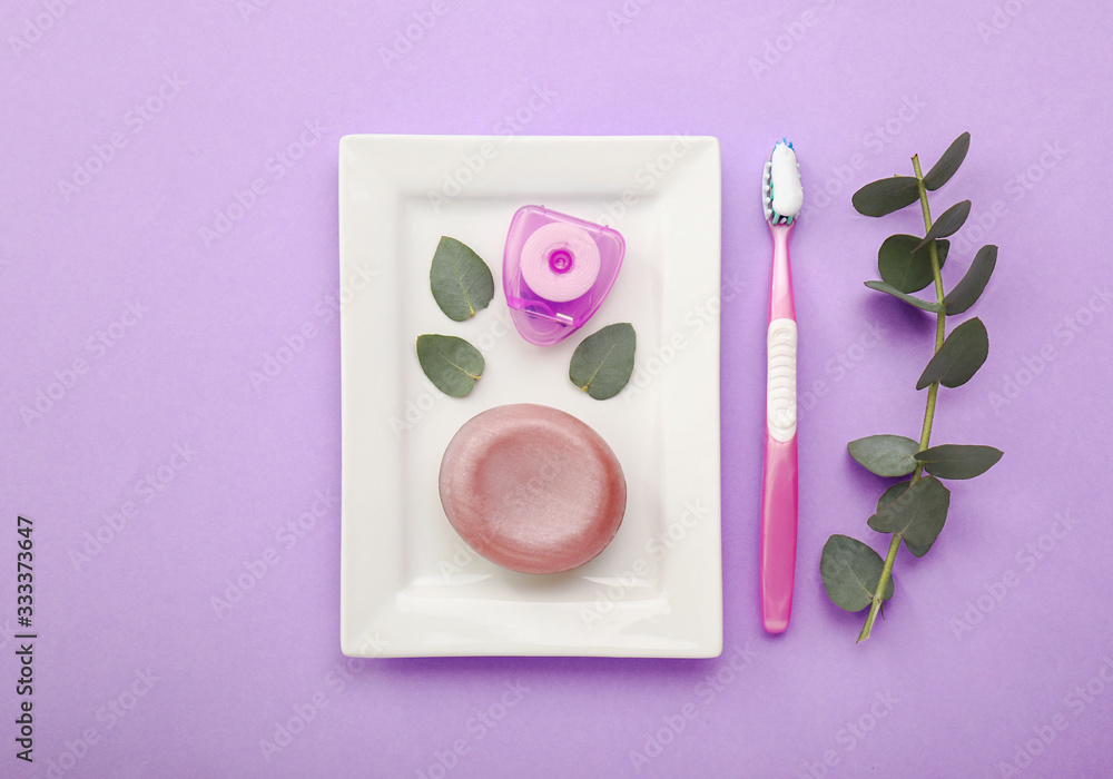 Tooth brush with paste, floss and soap on color background