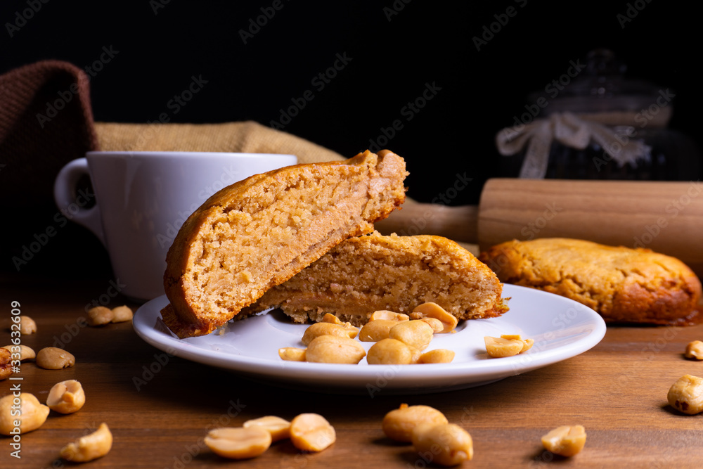 新鲜的纯素食饼干蛋糕，在木板上放花生酱、花生和一杯咖啡，并附上副本