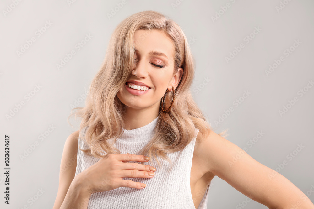 Young blonde with beautiful hair on light background