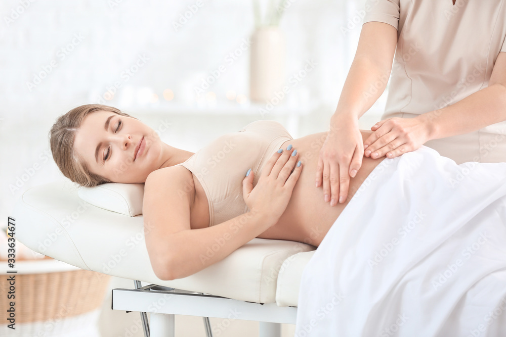 Young pregnant woman having massage in spa salon