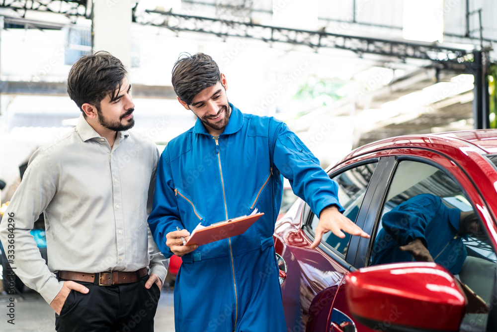 Vehicle maintenance handsome man servicer explain car condition, point at vehicle part to male custo