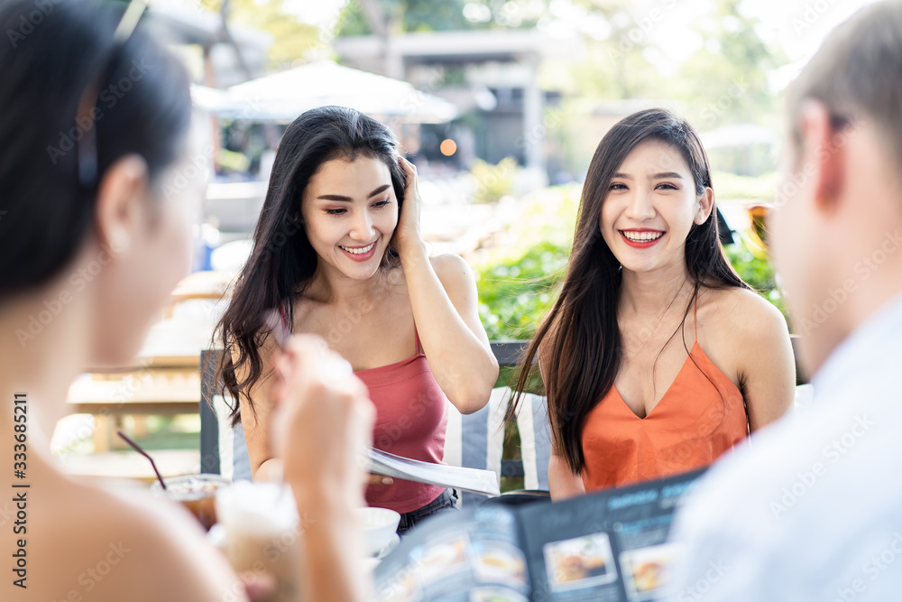 一群亚洲最好的朋友坐在户外餐厅点午餐。女孩们坚持